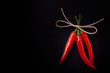 Three hot red chili pepper related by twine with on a black back