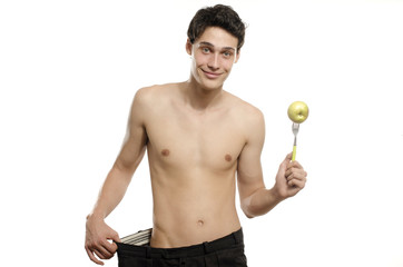 Wall Mural - Skinny young man with large pants eating an apple,anorexic look