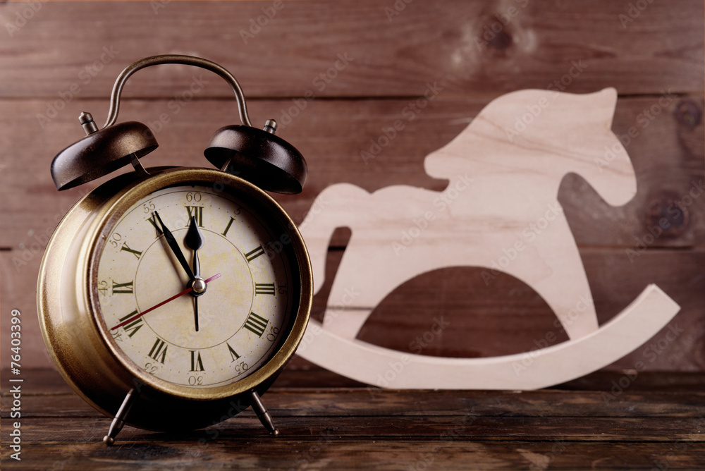 Retro clock with decorative horse on table on wooden background