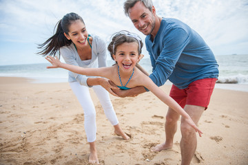 A loving six year old playing with mom and dad at the beach