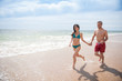 © jackfrog - A young couple runs in the sea waves in swimsuit