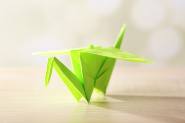 Wall Mural - Origami crane on wooden table, on light background