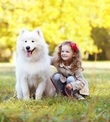 Wall Mural - Child and dog having fun outdoors in warm sunny day