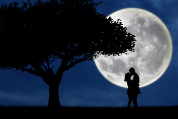 silhouette of couple kissing on blue full moon