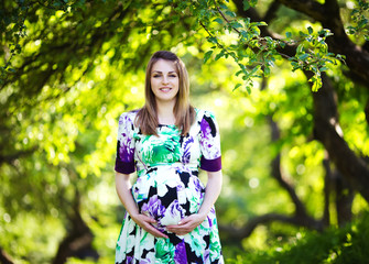 Beautiful pregnant woman in sunny park