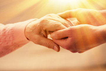 Wall Mural - Old and young holding hands on light background, closeup