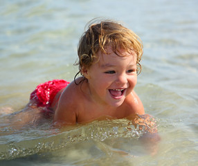 child bathing in sea on beach