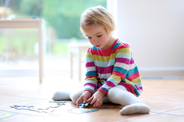 Toddler girl playing on the floor with jigsaw puzzle