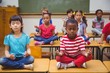 © WavebreakMediaMicro - Pupils meditating in lotus position on desk in classroom
