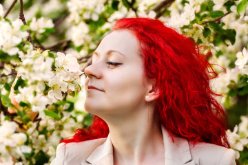 the girl with red hair in the blossoming garden