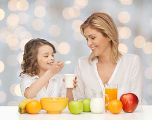 Canvas Print - happy mother and daughter eating breakfast