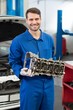 Smiling mechanic holding an engine