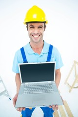 Poster - Happy repairman wearing hard hat while holding laptop
