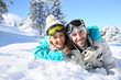 © goodluz - Cheerful couple of skiers laying down in snow