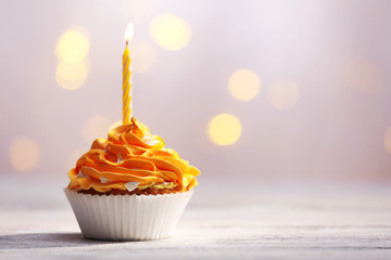 Delicious birthday cupcakes on table on light background