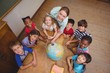 © WavebreakMediaMicro - Cute pupils smiling around a globe in classroom with teacher