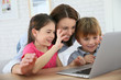 © goodluz - Family of three using laptop video call camera