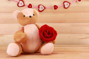 Wall Mural - Teddy bear with rose on wooden background, love concept