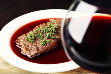 Wall Mural - Glass of wine with steak on wooden background