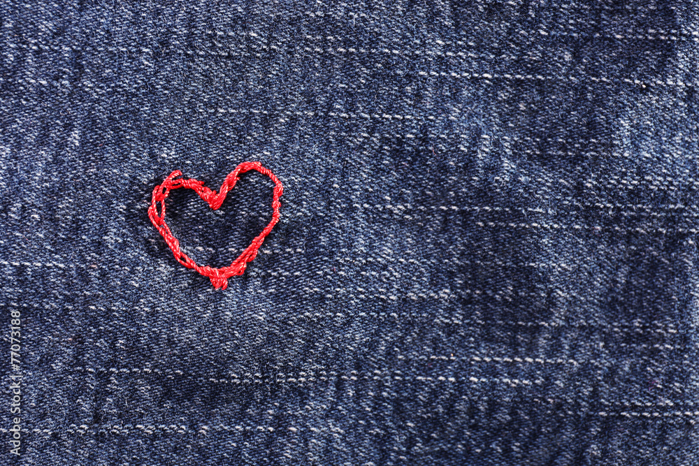 Jeans fabric with red heart embroidered on it, close-up