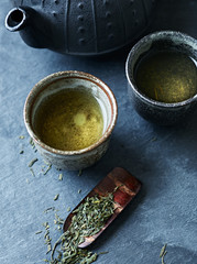 A cast iron tea pot and green tea in ceramic cups