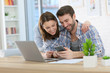© goodluz - Couple at home using smartphone in front of laptop