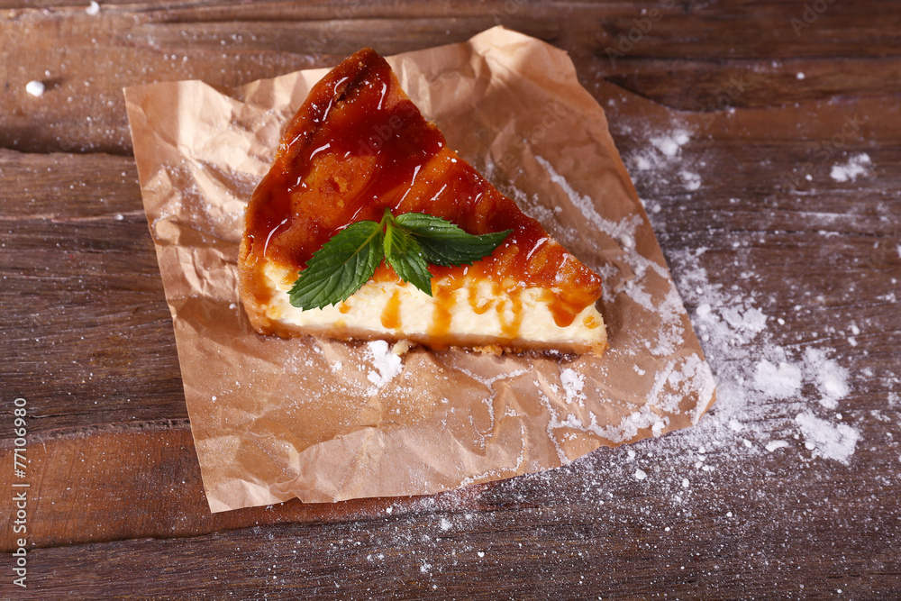 Cheese cake with sugar powder on paper on wooden background