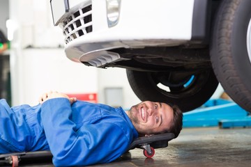 Poster - Smiling mechanic lying on trolley