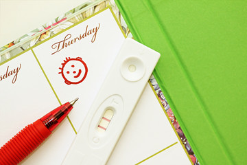 Pregnancy test with a positive result and female diary.