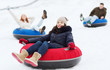 © Syda Productions - group of happy friends sliding down on snow tubes