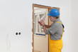 © sima - Worker installing wooden door, using polyurethane foam