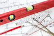 Wasserwaage, Bleistift, Zollstock und Zirkel auf einem Bauplan/Grundriss