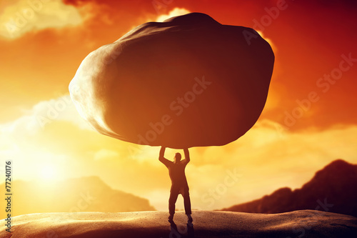 Fotografia Man lifting a huge rock. Concept of strength, ballast, power