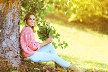 Happy stylish pretty woman with maple leafs outdoors