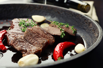 Steak in frying pan on table close up