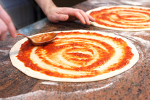 Tomato Sauce Being Spread On Pizza Base.