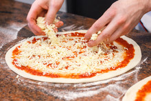 Cheese Being Spread On Tomato Sauce On Pizza Base.