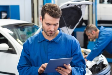 Poster - Smiling mechanic using a tablet pc