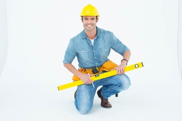 Poster - Worker using spirit level while kneeling over white background