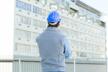 Poster - Architect wearing hard hat while looking at building