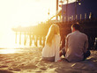 © Joshua Resnick - romantic couple sitting together by the beach with sunset