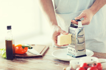 close up of male hands grating cheese