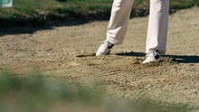 Man Golfer On A Sand Golf Course Hitting White Golf Ball