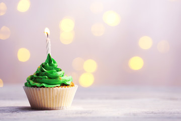 Wall Mural - Delicious birthday cupcake on table on light background