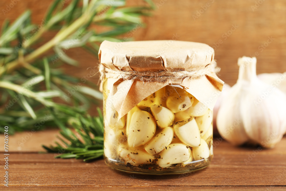 Canned garlic in glass jar on wooden background