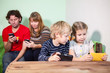 © Kekyalyaynen - Children with parents sit with gadgets, playing game in phones