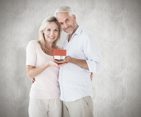 Poster - Composite image of happy couple holding miniature model house
