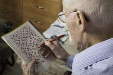 A Elderly Man Sitting Doing Crosswords Hobby