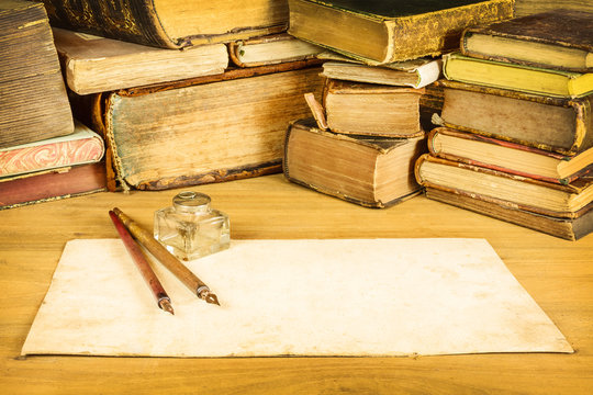Fountain pens with paper in front of old books