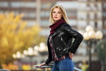 Young fashion blond woman in leather jacket on the city street